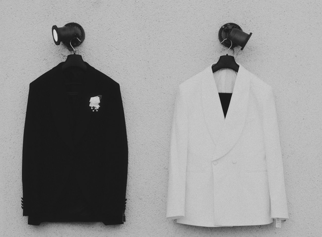 Pair of contrasting black and white suit jackets hanging on wall, perfect for formal occasions.